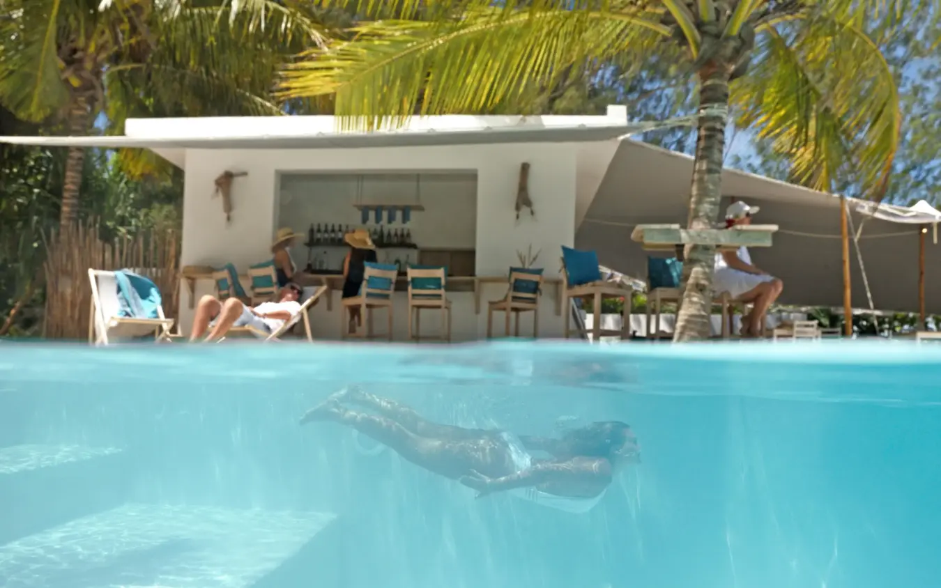 Swimming pool with guest lounging underwater near beachfront bar, Sharazad Boutique Hotel, Zanzibar & Pemba, Tanzania
