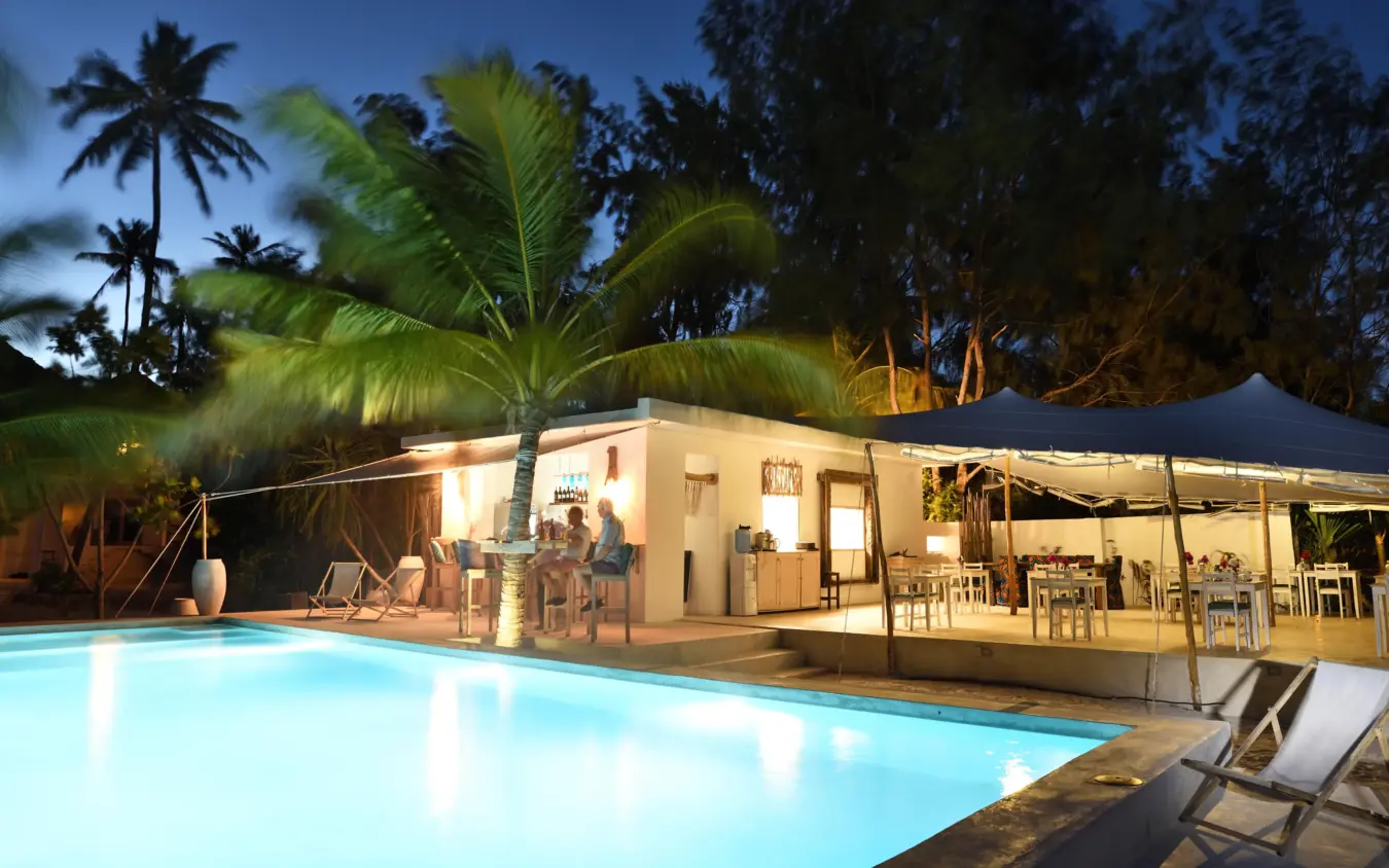 Illuminated poolside with lounge building and palm trees at dusk, Sharazad Boutique Hotel, Zanzibar & Pemba, Tanzania