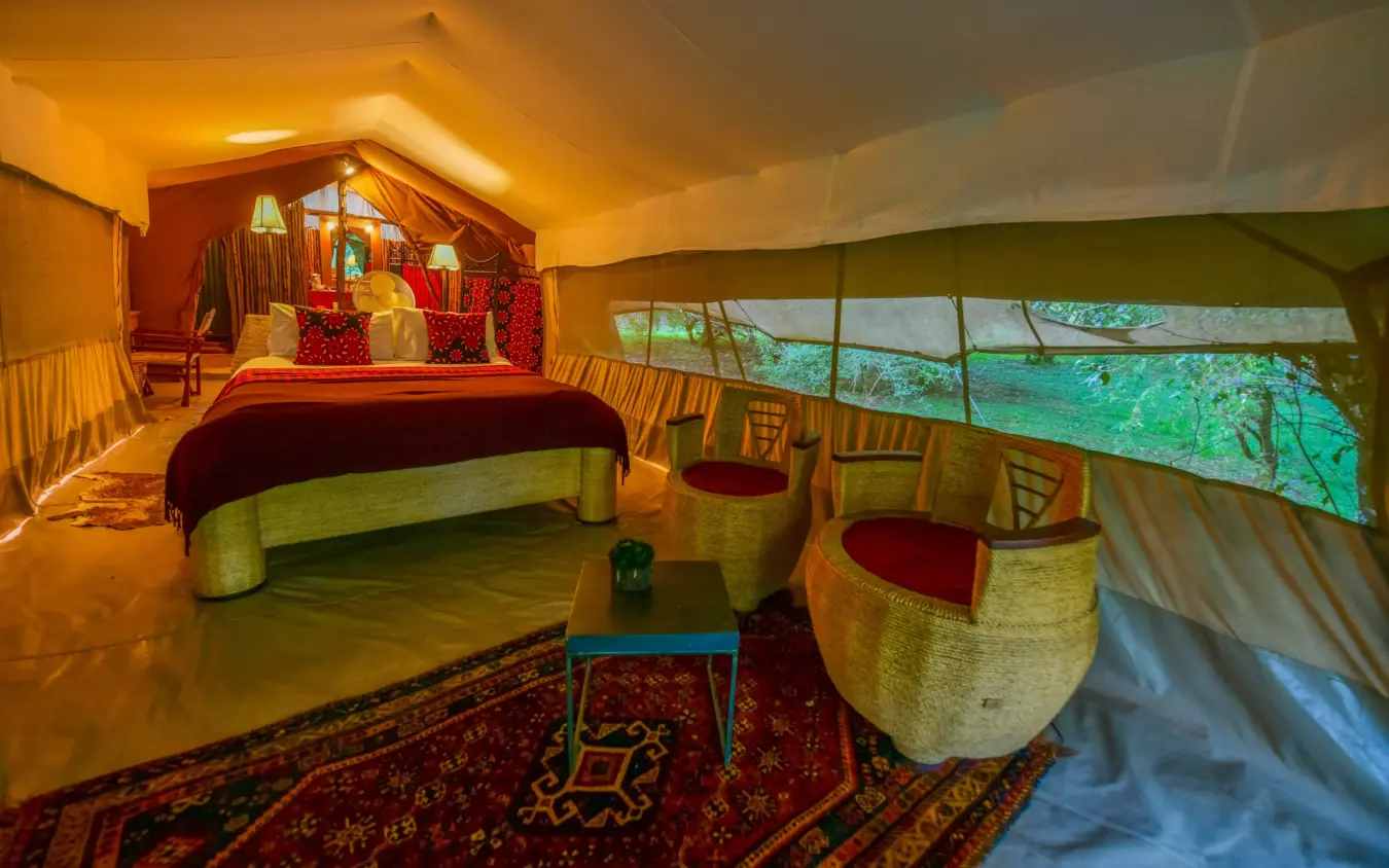 Luxury tent bedroom with canvas walls and forest views, Speke’s Camp, Maasai Mara, Kenya