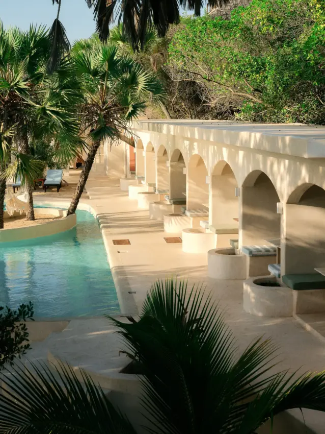 Shaded arcaded structure beside turquoise spring pool with palm trees, The Cabanas, Lamu Archipelago, Kenya