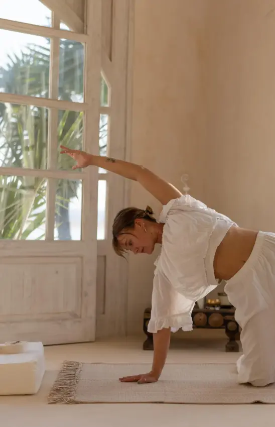 Woman practicing yoga in bright room with garden doors, The Cabanas, Lamu Archipelago, Kenya