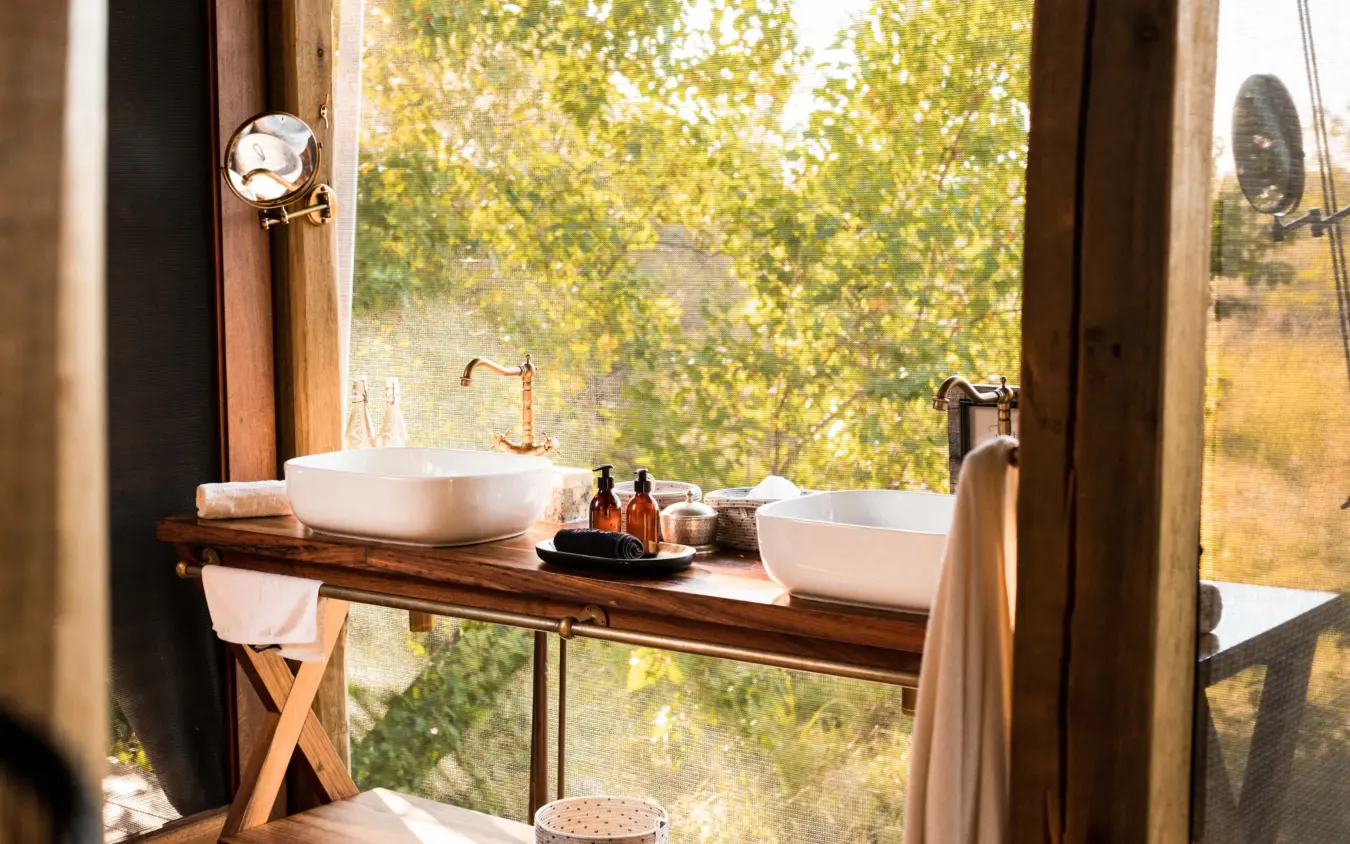 Outdoor bathroom vanity with twin basins overlooking woodland landscape, Tuludi, The Okavango Delta, Botswana