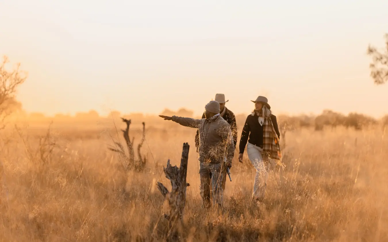 Two guides walking through dry grassland at golden hour, Savuti Camp, Linyanti Wildlife Reserve, Botswana