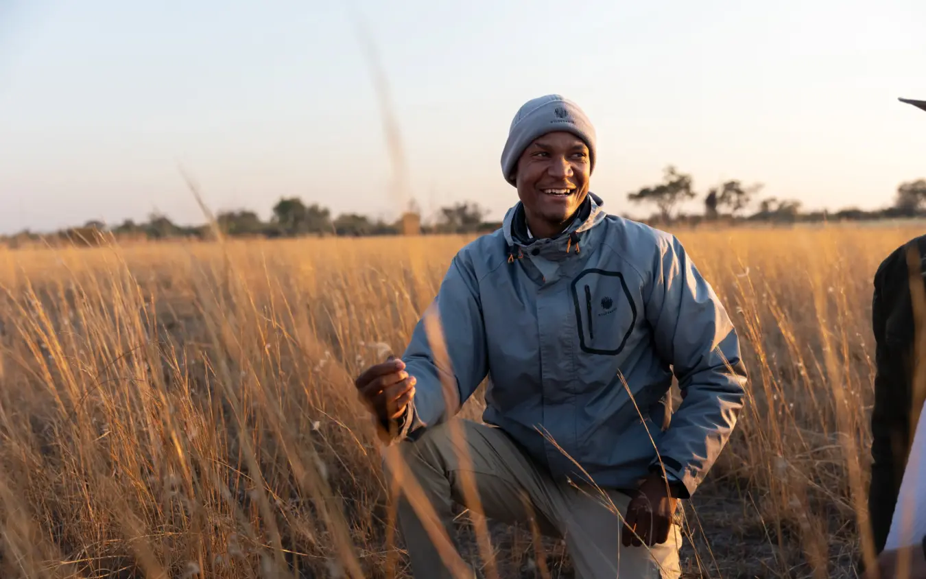 Man jogging through golden grassland at sunset with hot air balloons in background, Savuti Camp, Linyanti Wildlife Reserve, Botswana
