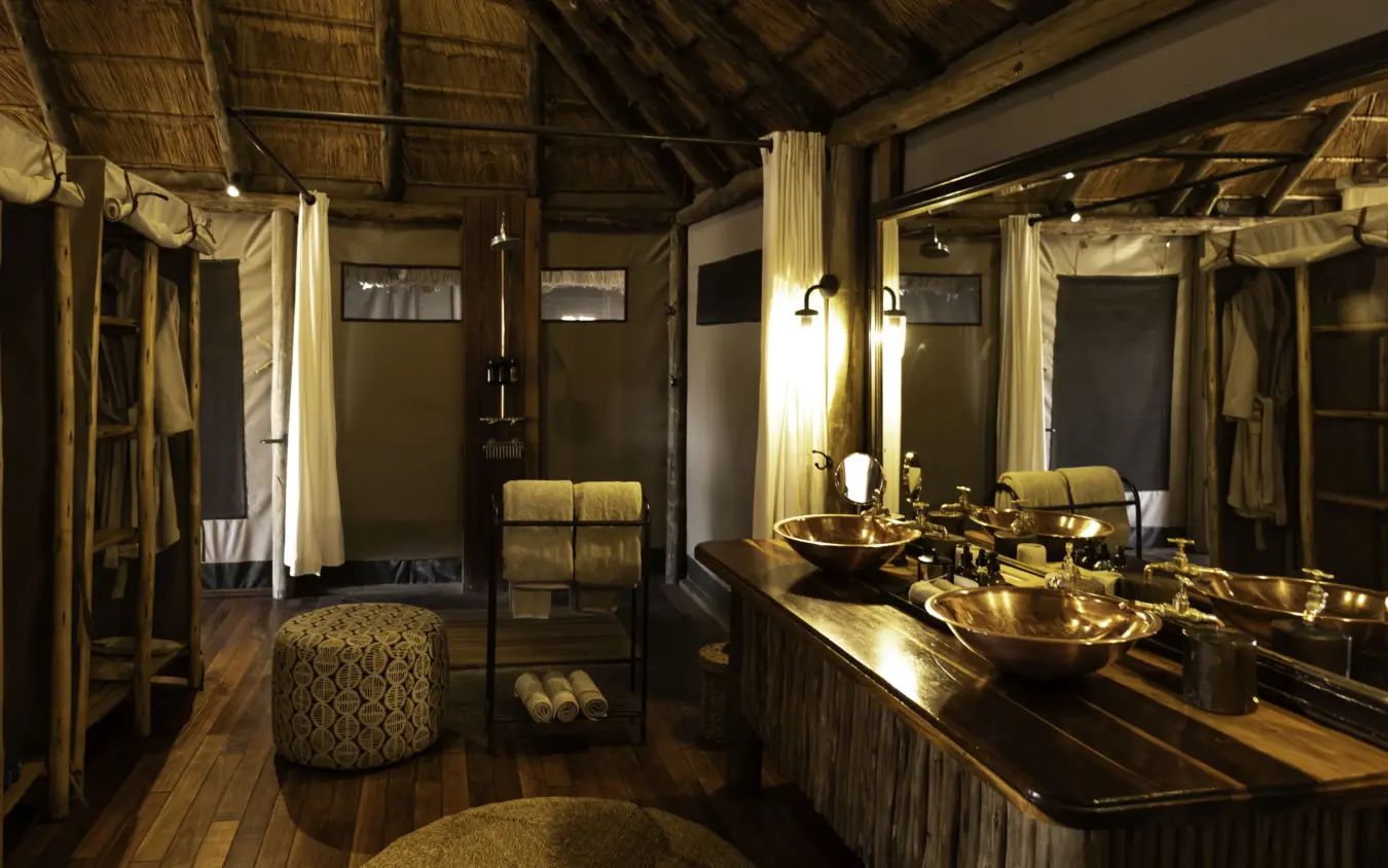 Luxury bathroom interior with twin vessel sinks and mirror lighting at night, Savuti Camp, Linyanti Wildlife Reserve, Botswana