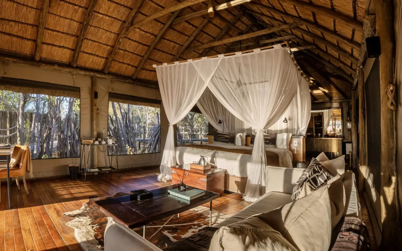 Luxury safari suite with four-poster bed and lounge area overlooking woodland, Savuti Camp, Linyanti Wildlife Reserve, Botswana