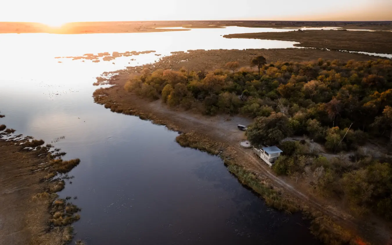 Aerial view of riverside lodge nestled among mangrove forests at sunset, Savuti Camp, Linyanti Wildlife Reserve, Botswana