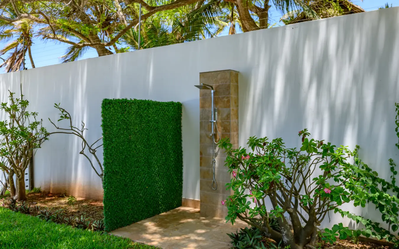 Outdoor shower with tiled column beside artificial green hedge wall, Bahari Bliss, Kilifi, Kenya