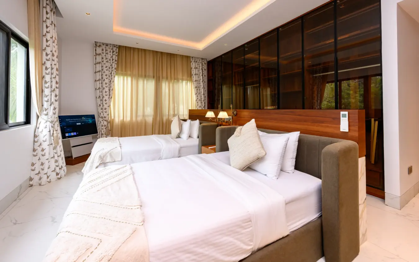 Twin beds with white linens in bedroom beside wall of dark glass panels, Bahari Bliss, Kilifi, Kenya